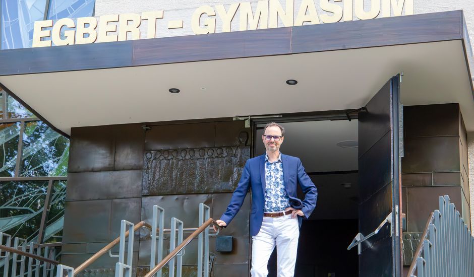 Mann steht vor dem Eingang, über dem "Egbert-Gymnasium" in goldenen Lettern steht