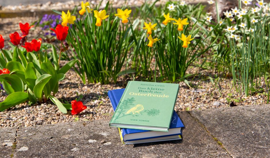 Bücherstapel vor einem Blumenbeet