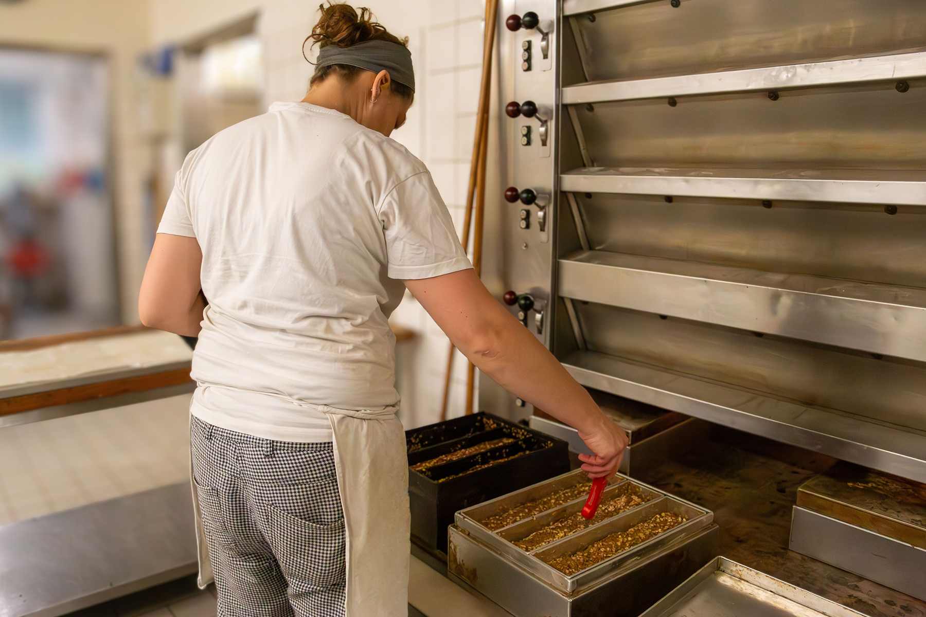 Frau steht am Ofen und misst Temperatur in Brotform