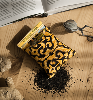 Tee-Tütchen mit gelb-schwarzem Muster auf Holztisch 