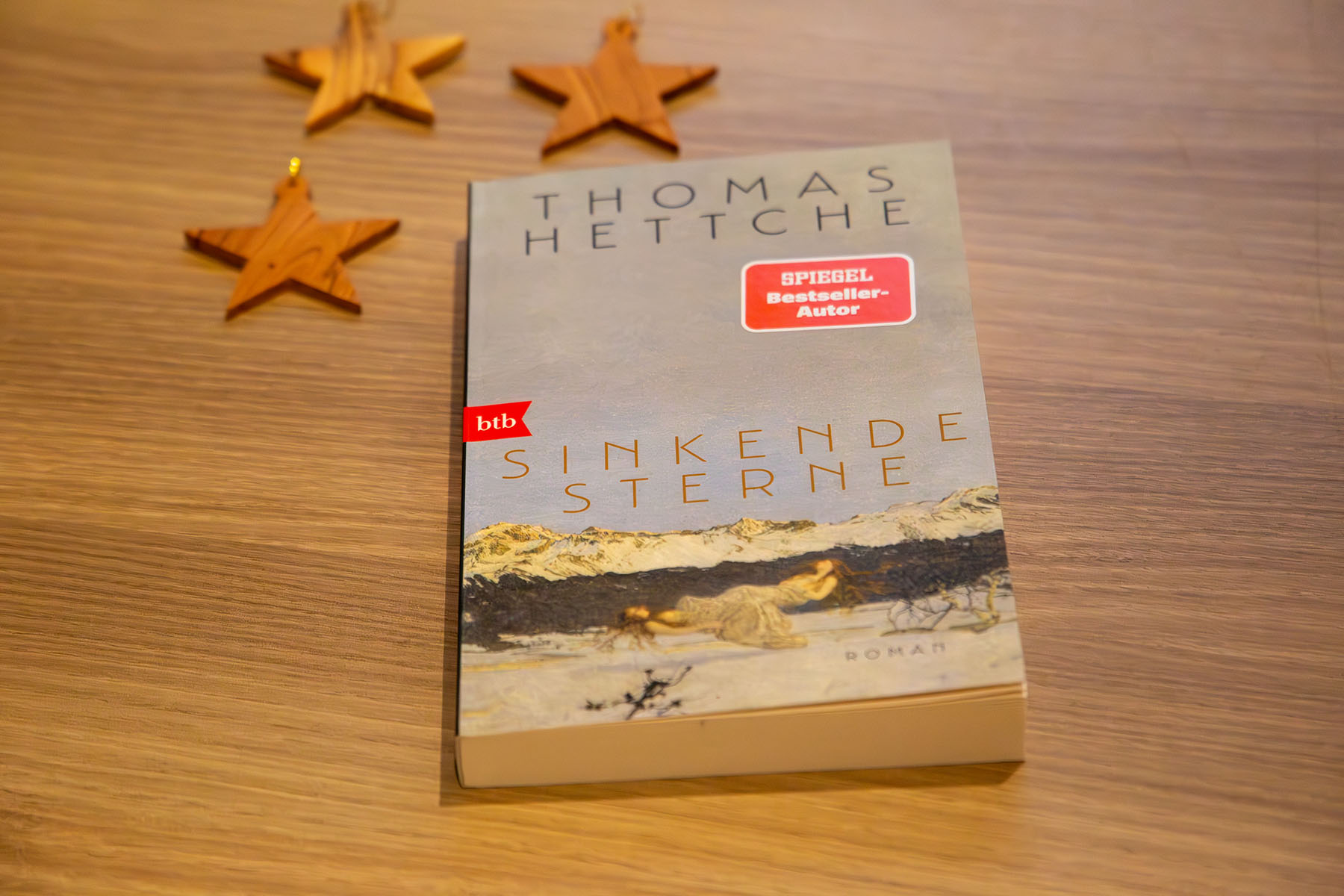 Buch "Sinkende Sterne" auf einem Holztisch liegend