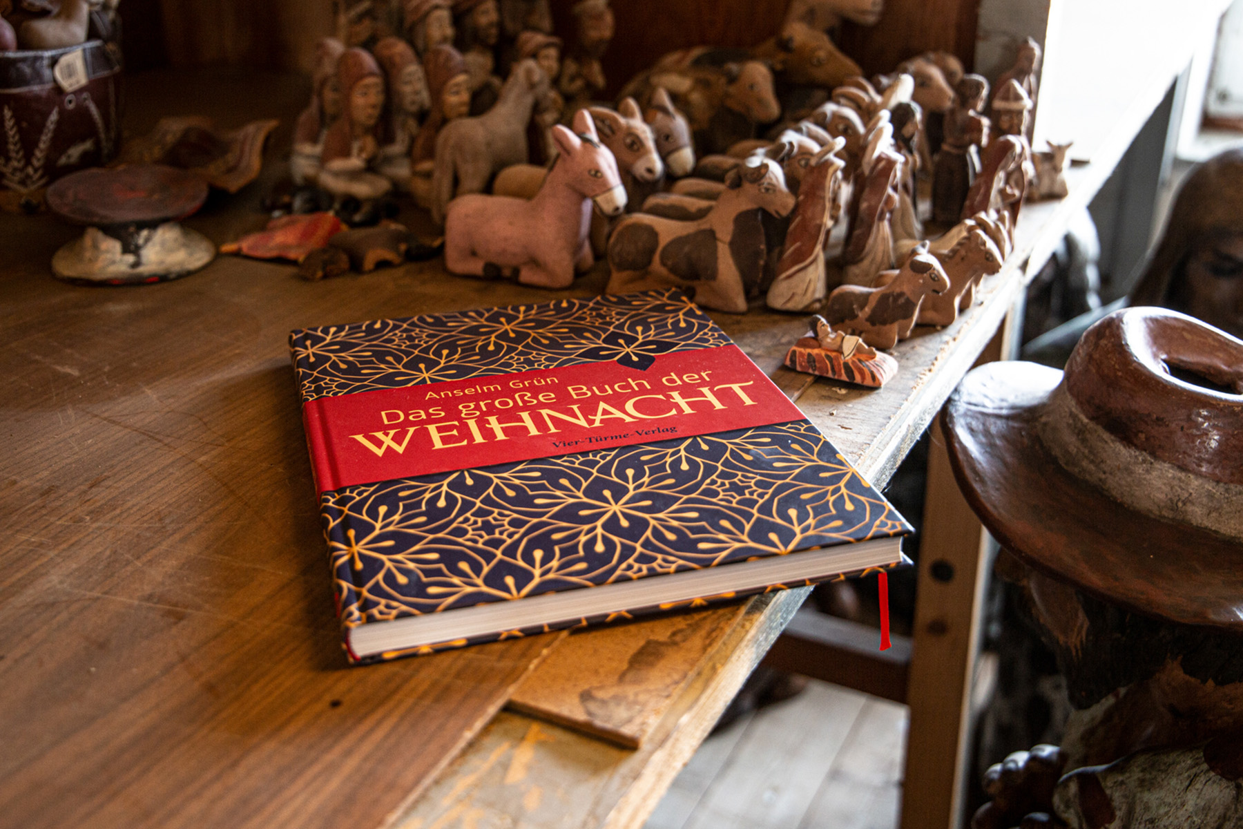 Buch auf einem Holztisch, auf dem Krippenfiguren stehen