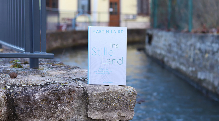 Bild auf einer Steinmauer neben der ein Fluss fließt