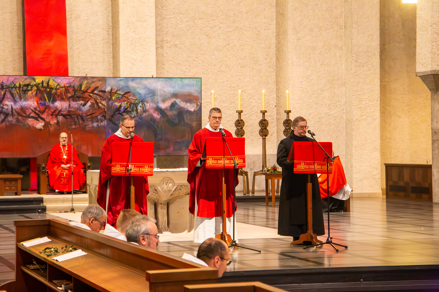 Drei Mönche in roten Gewändern an Mikrophonen