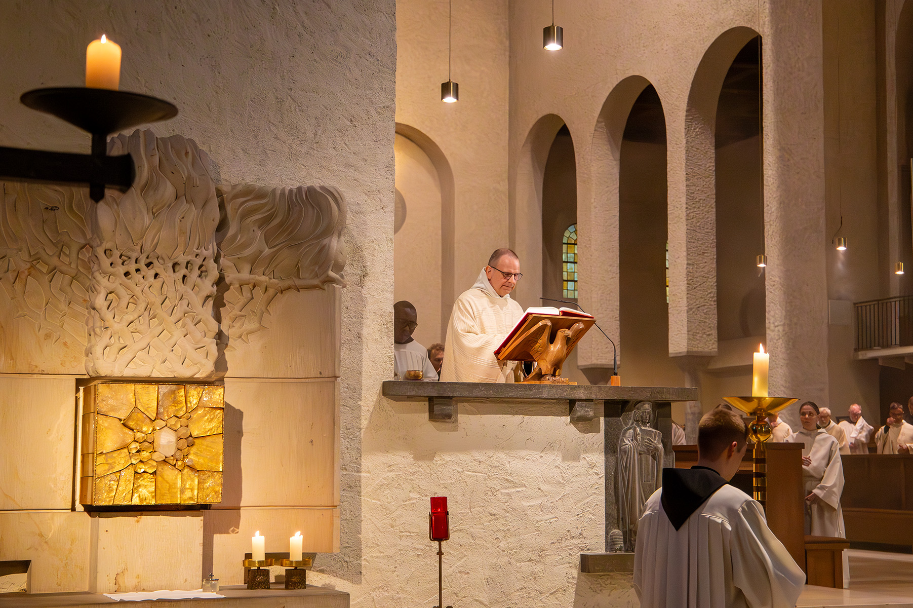 Pater auf Kanzel mit großer roter Bibel