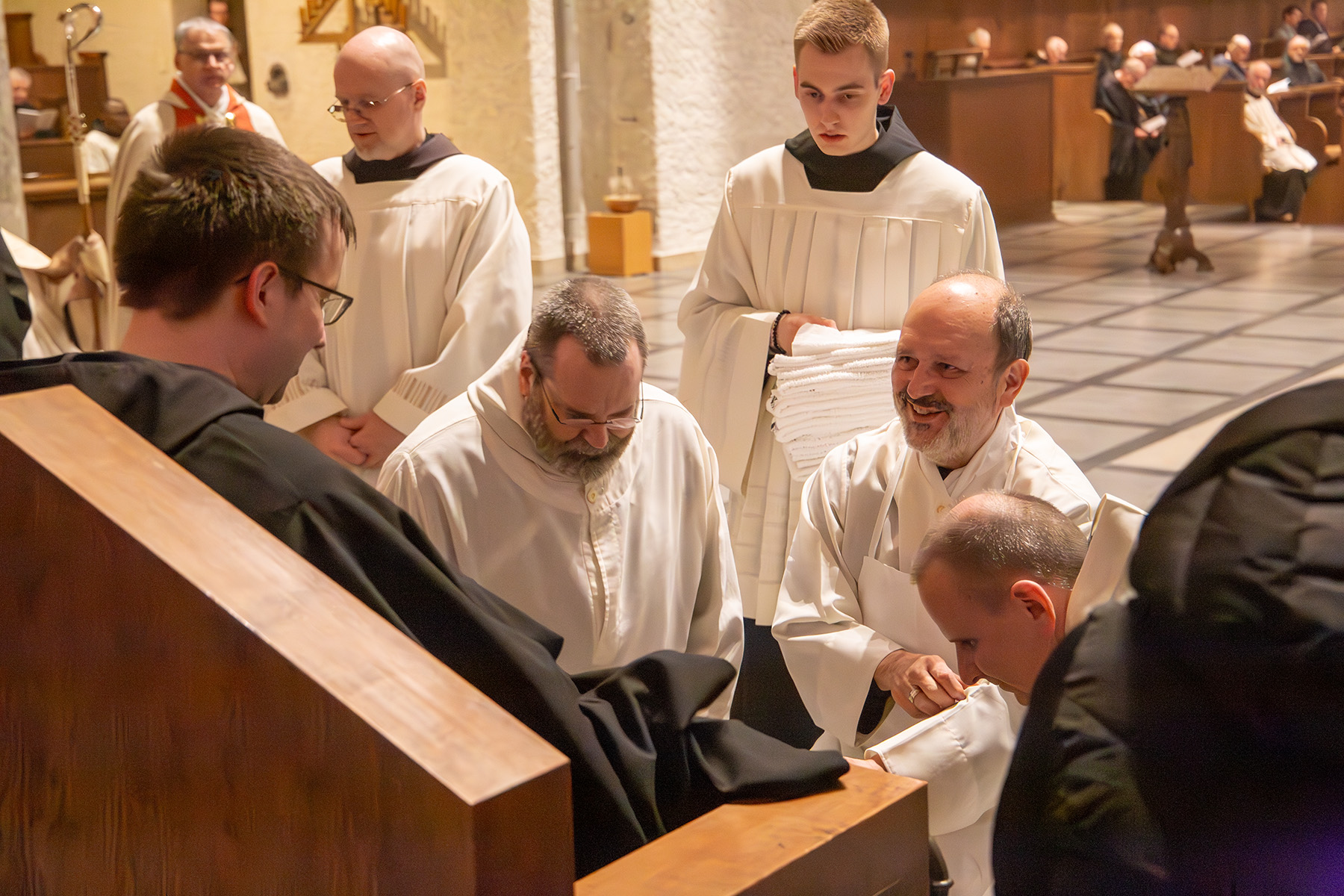Mönche stehen um einen jungen Mann herum, der die Füße gewaschen bekommt