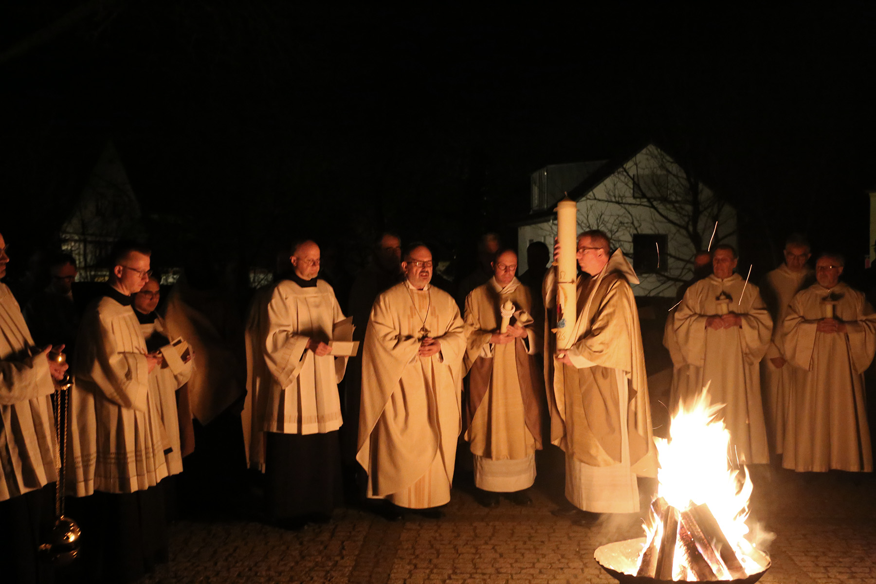 Mönche mit großer Kerze vor Feuer
