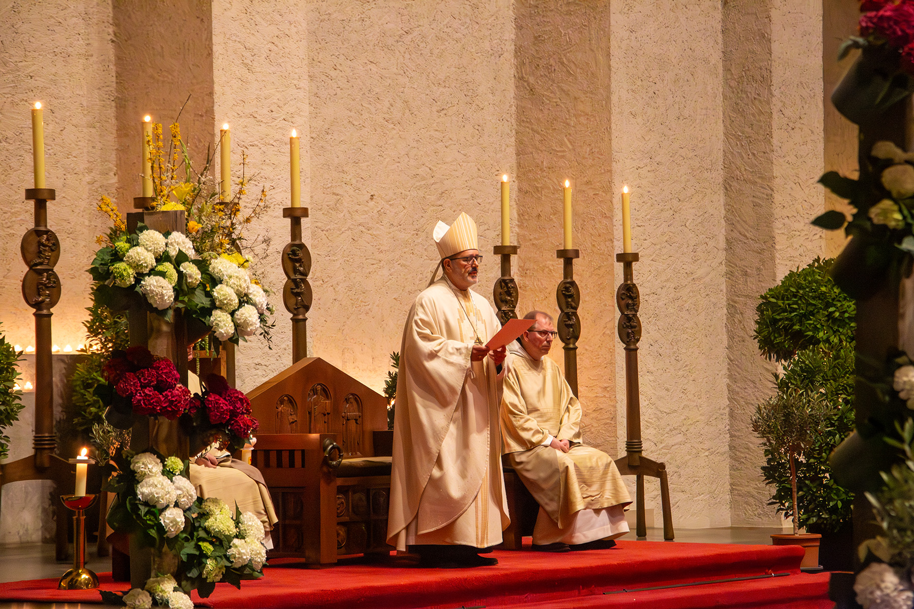 Ein Mönch steht, ein Mönch sitzt neben ihm auf einen Stuhl