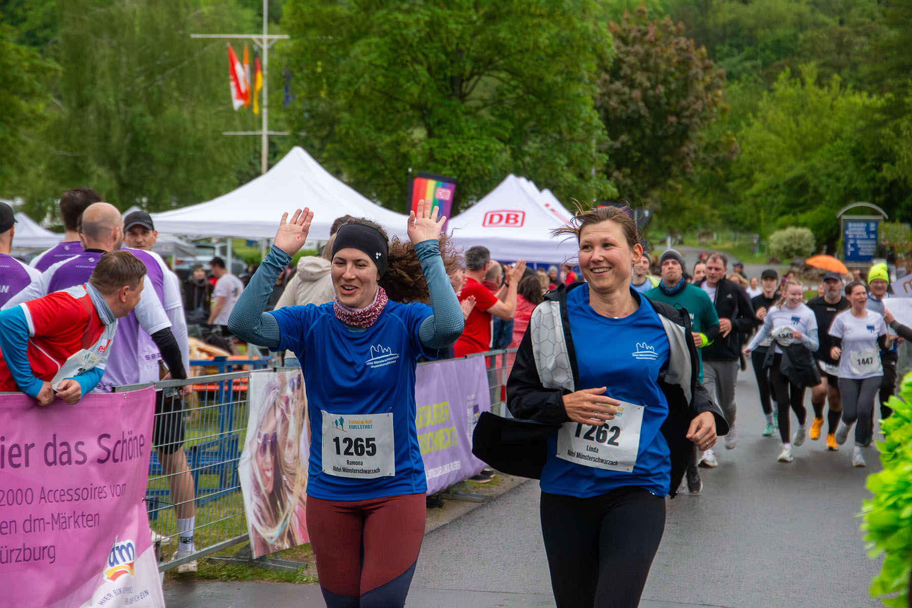 Zwei junge Frauen in Sportkleidung am Ziel, die linke wirft die Hände in die Luft