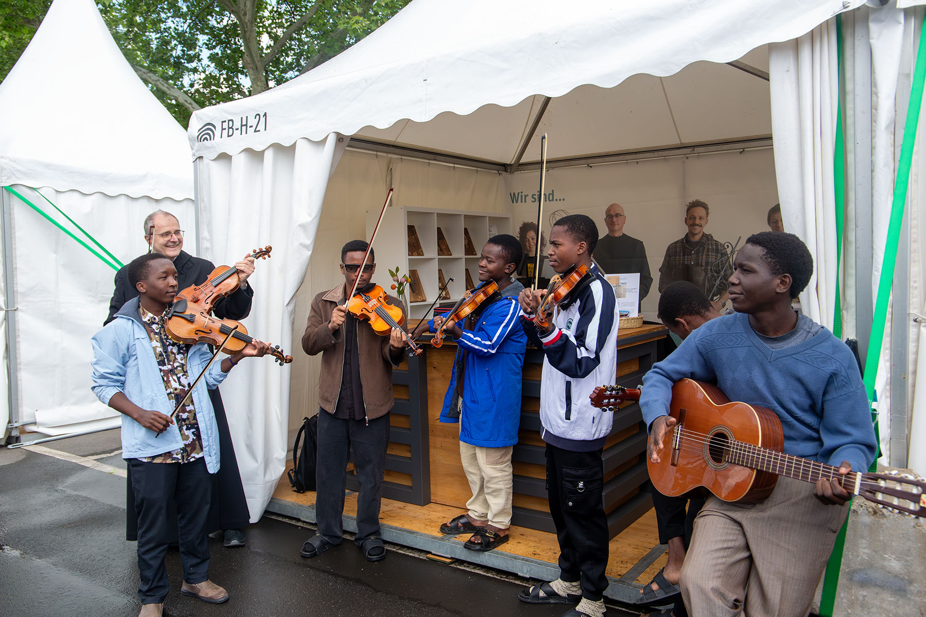 Afrikanische Männer und ein Mönch beim Musizieren mit Gitarre und Geigen