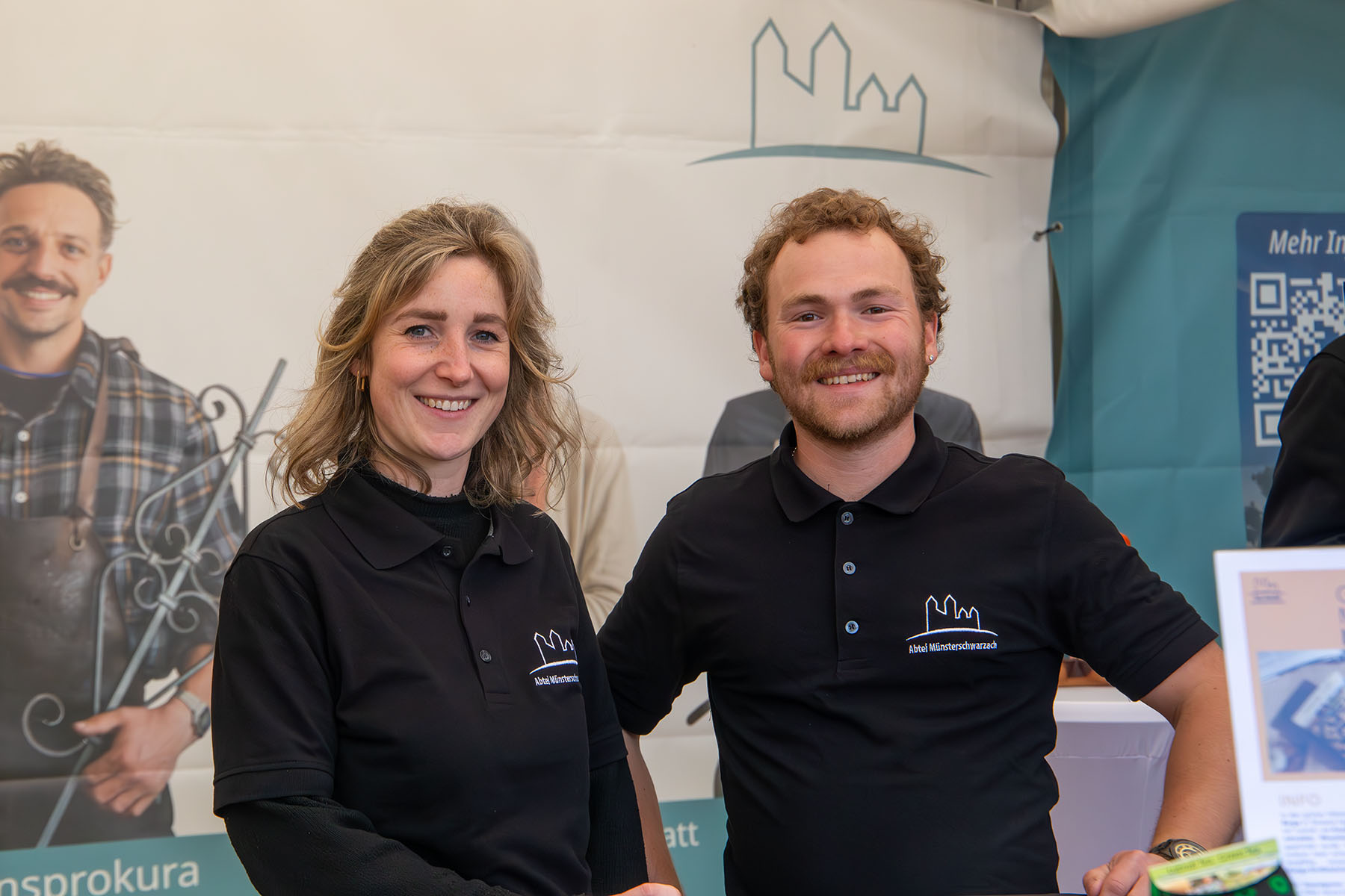 Junge Frau und junger Mann im Poloshirt mit Abtei-Logo
