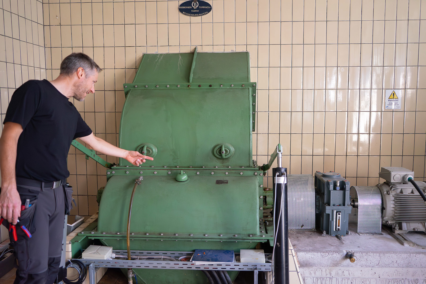 Mann steht neben einer grünen Turbine