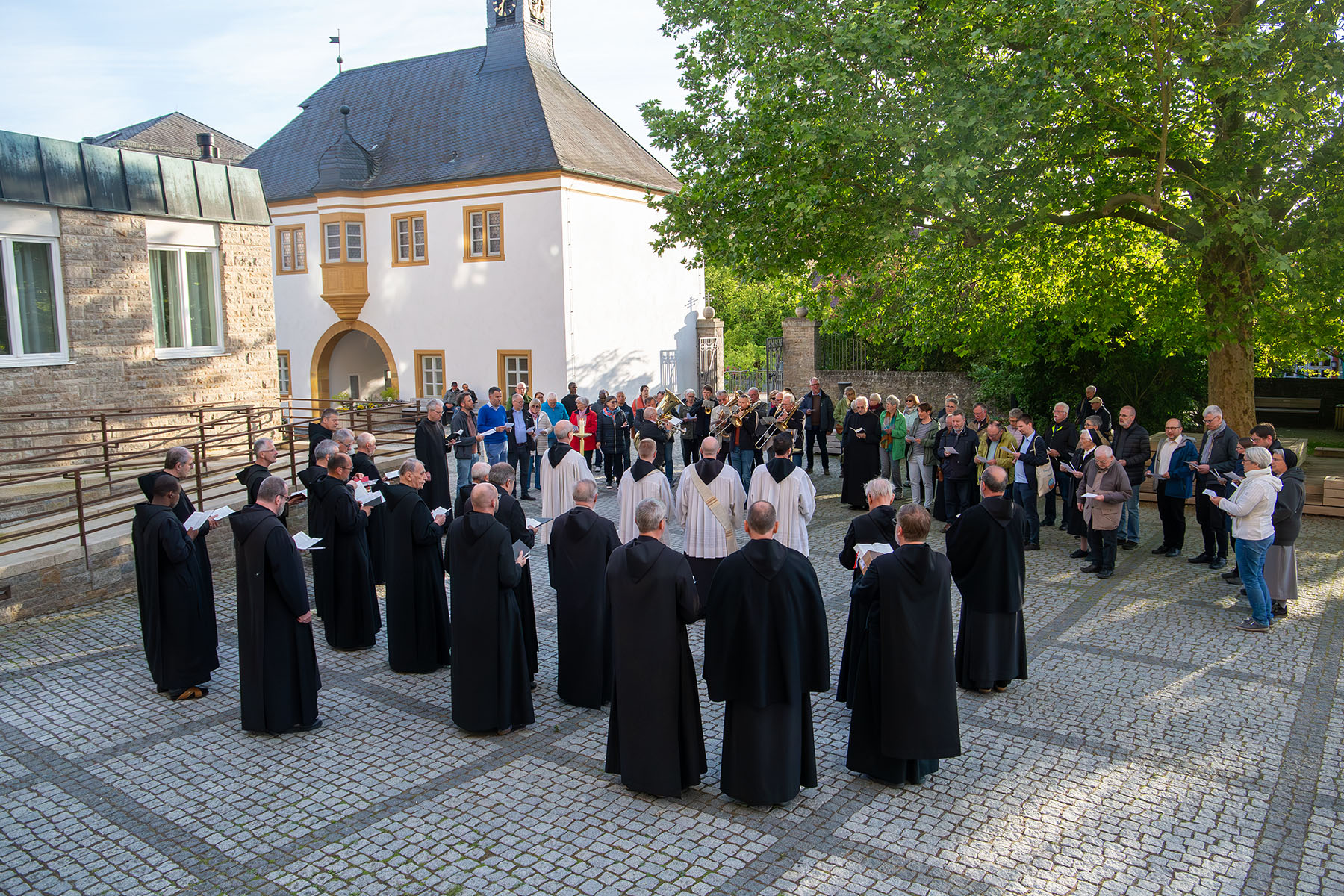Blick über Platz auf dem viele Menschen stehen, davon auch eine Reihe Mönche im Habit