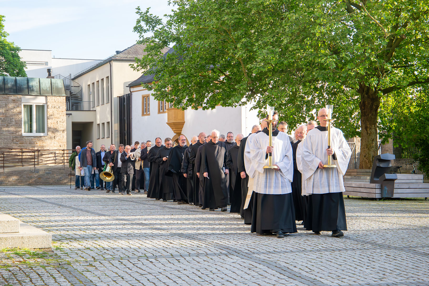Lange Schlange mit Mönchen, an der Spitze Männer mit weißem Gewandt und Kerzen