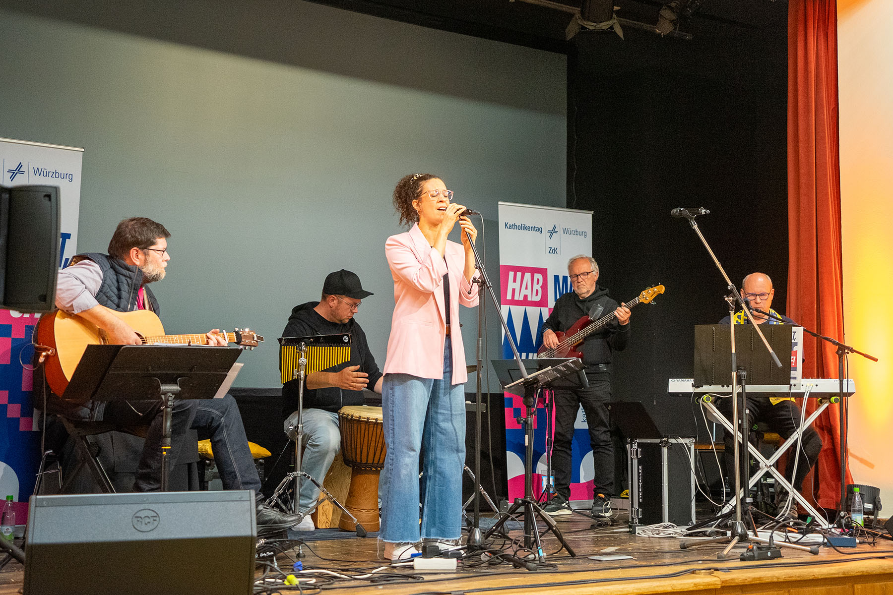 Vier Musiker mit Instrumenten und eine Sängerin auf einer Bühne