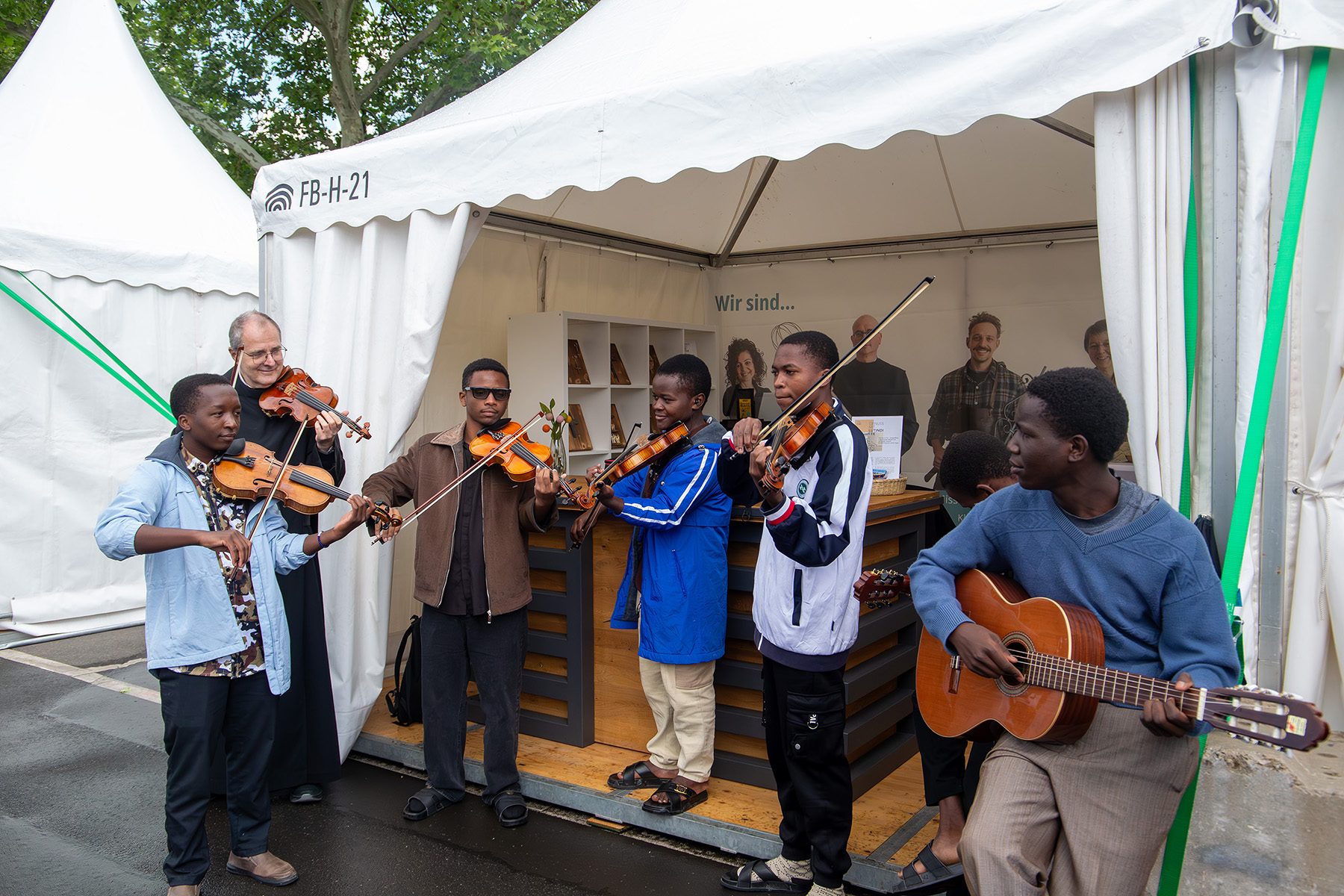 Gruppe mit 5 jungen Männern und einem Mönch mit Geigen und einer Gitarre