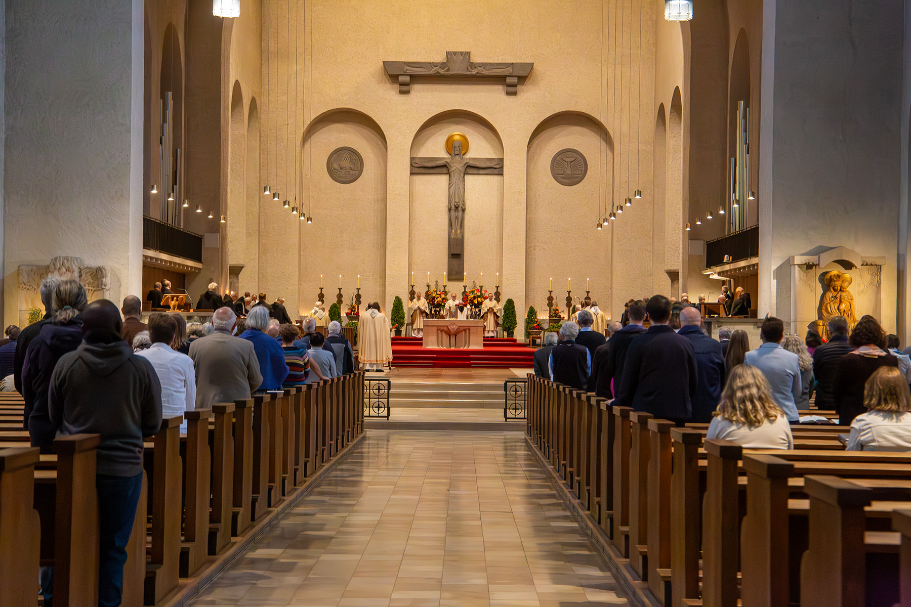 Blick in Kirche auf den Altar, links und rechts stehen Menschen in den Bänken