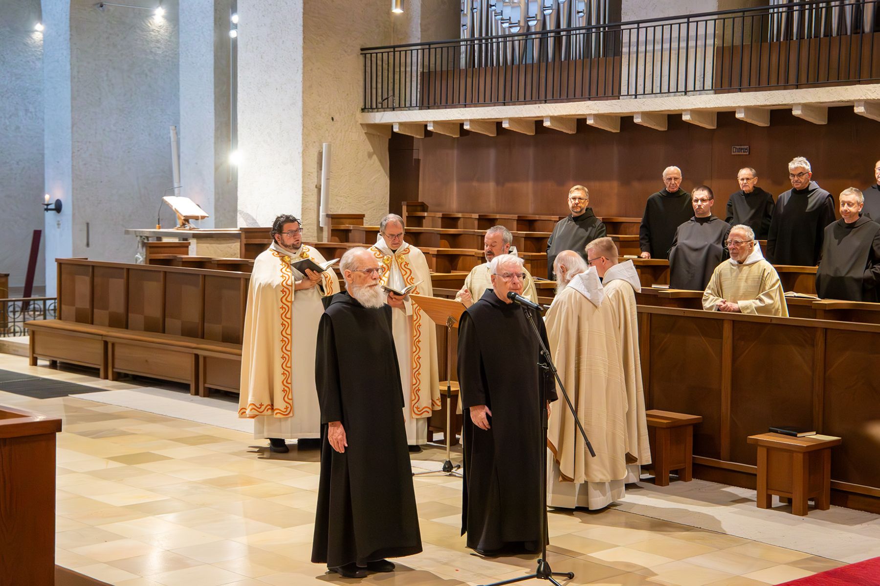 Zwei Männer im schwarzen Gewand stehen in der Kirche vor einem Mikrophon