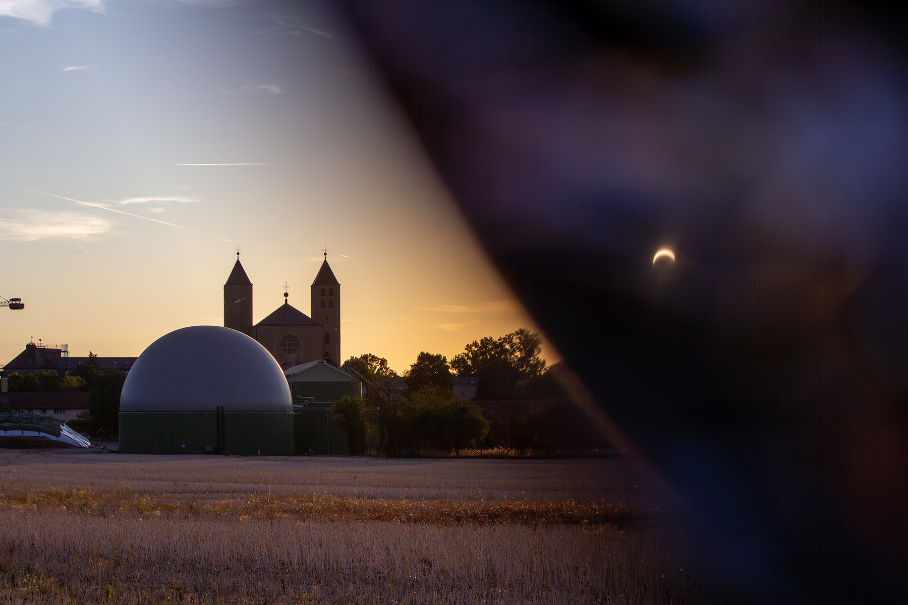 Abteikirche im Abendhimmel, auf der rechten Seite schwarze Fläche mit Umriss der Sonne
