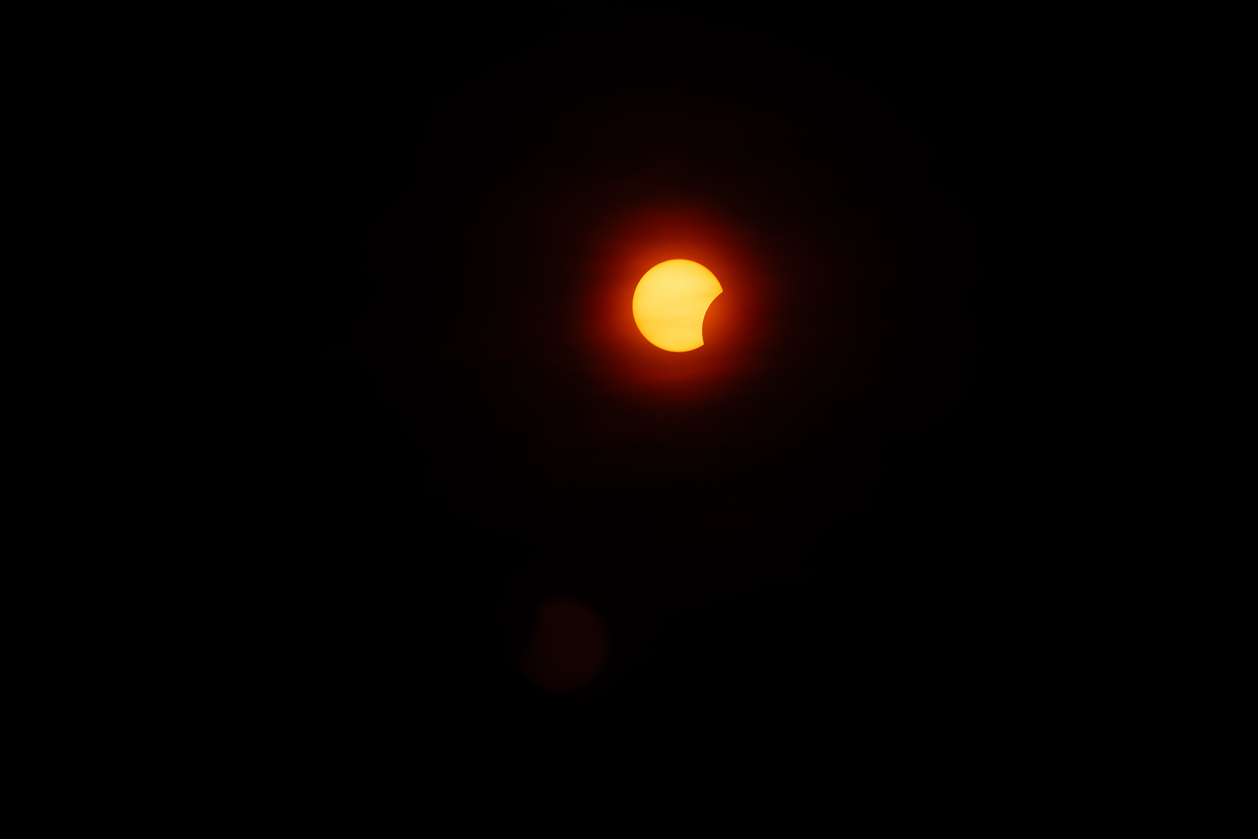 Sonne als roter Ball, ein Stück davon verdeckt