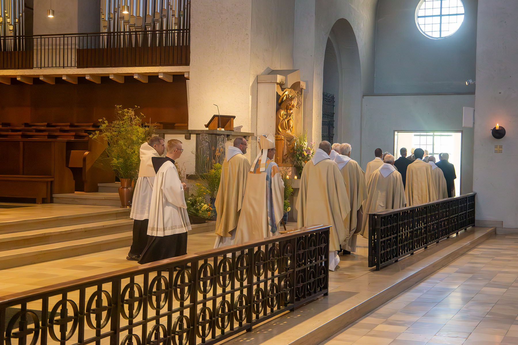 Gruppe von Mönchen in hellen Gewändern zieht aus Kirche aus