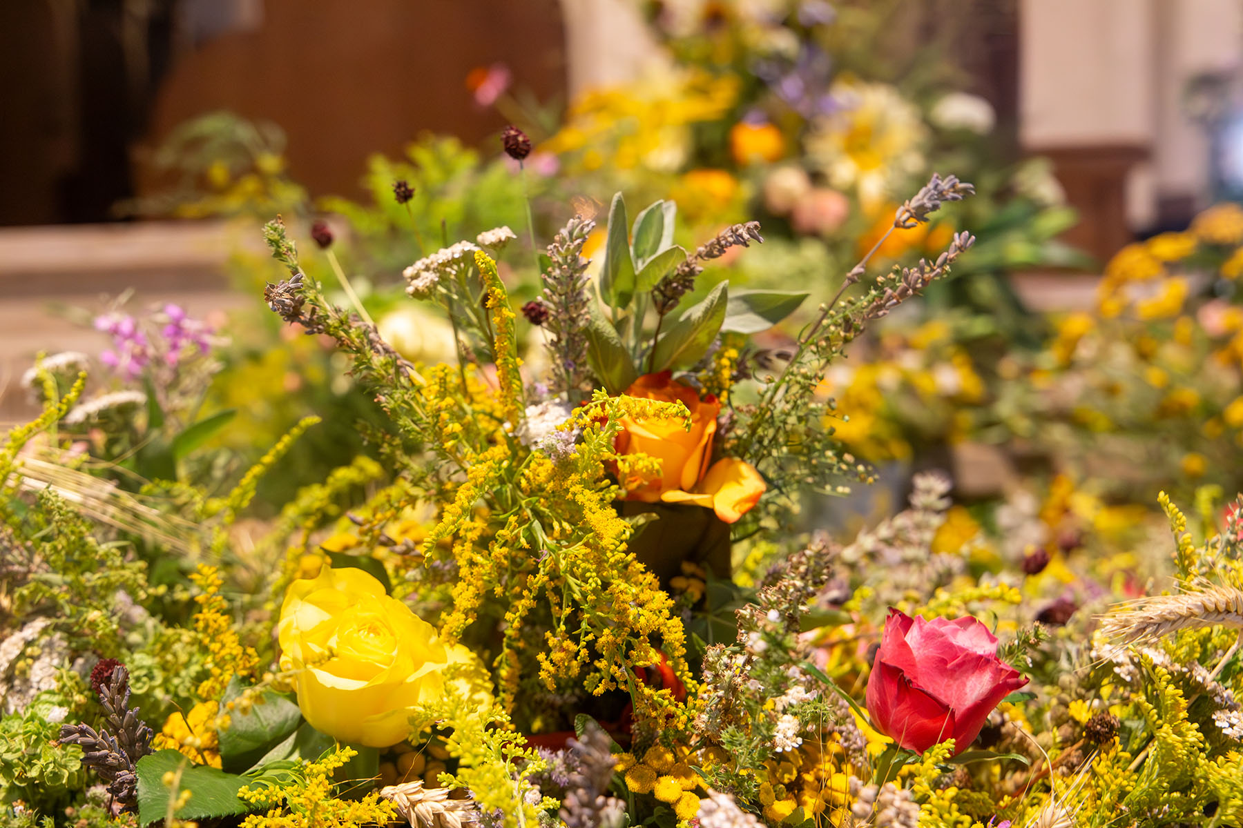 Blumenschmuck mit einer gelben, orangen und roten Rose