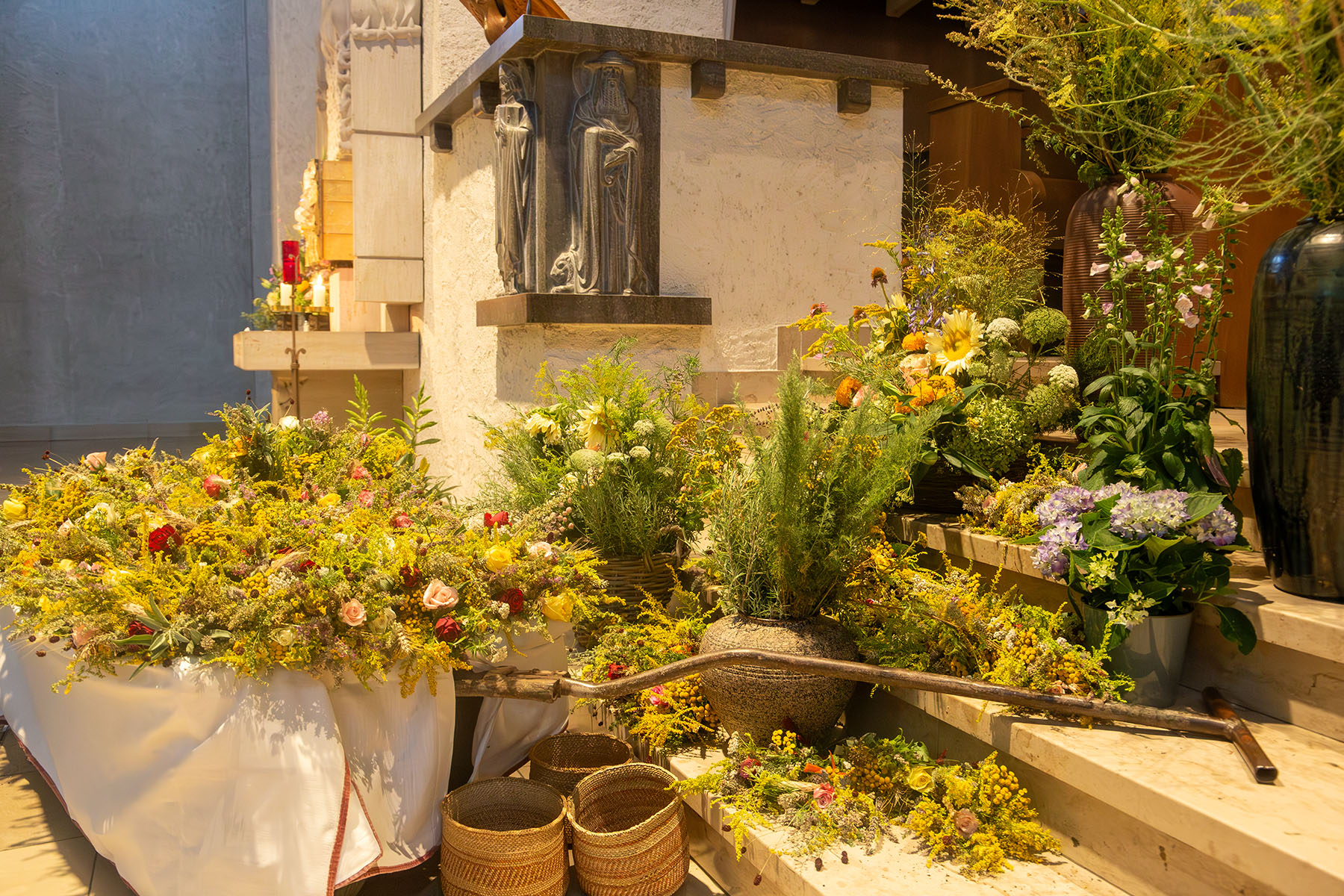 Wagen voller Blumen sowie weitere Gefäße mit Kräutern in der Kirche