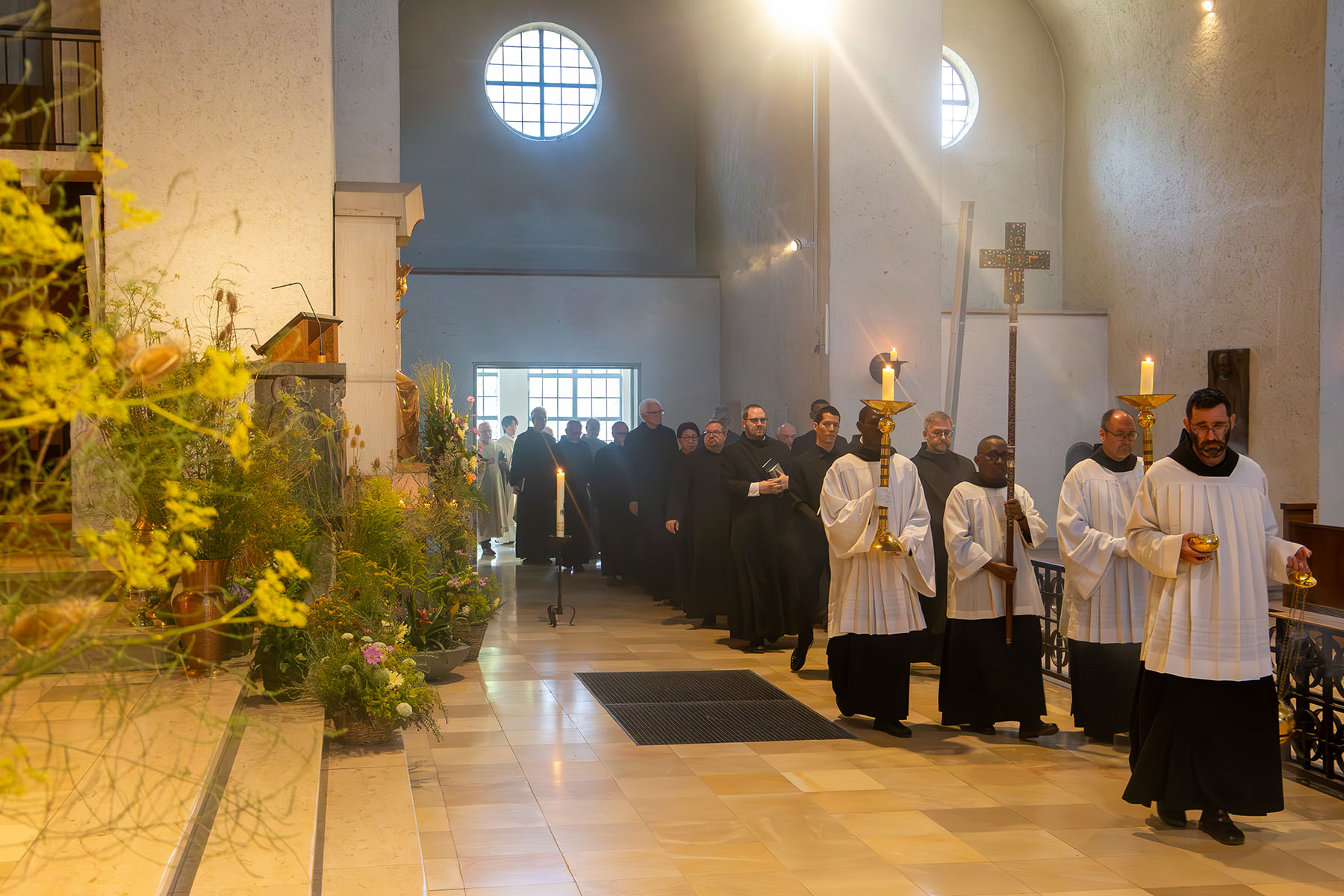 Gruppe von Mönchen ziehen mit Kreuz und Kerzen an der Spitze in die Kirche ein