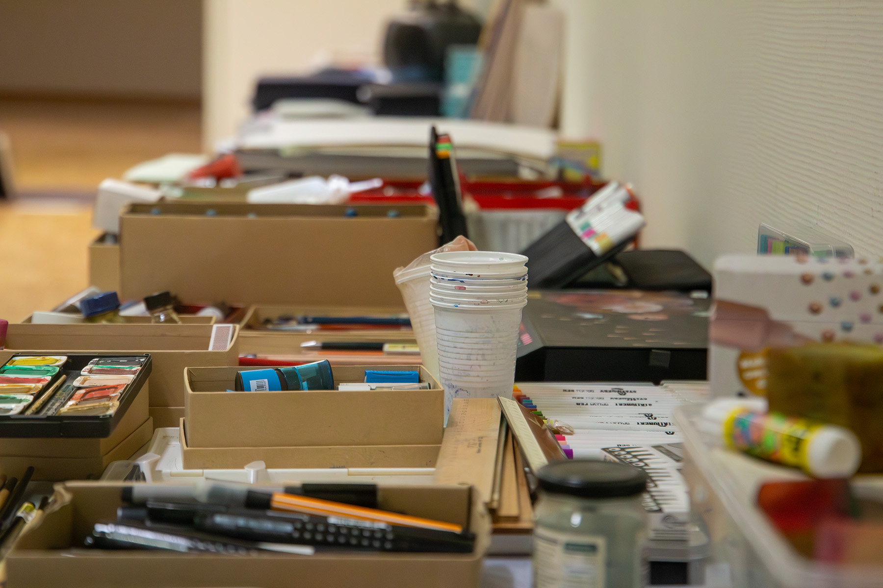 Blick auf ein Sammelsurium von Materialien: Stifte, Papier, Becher etc.