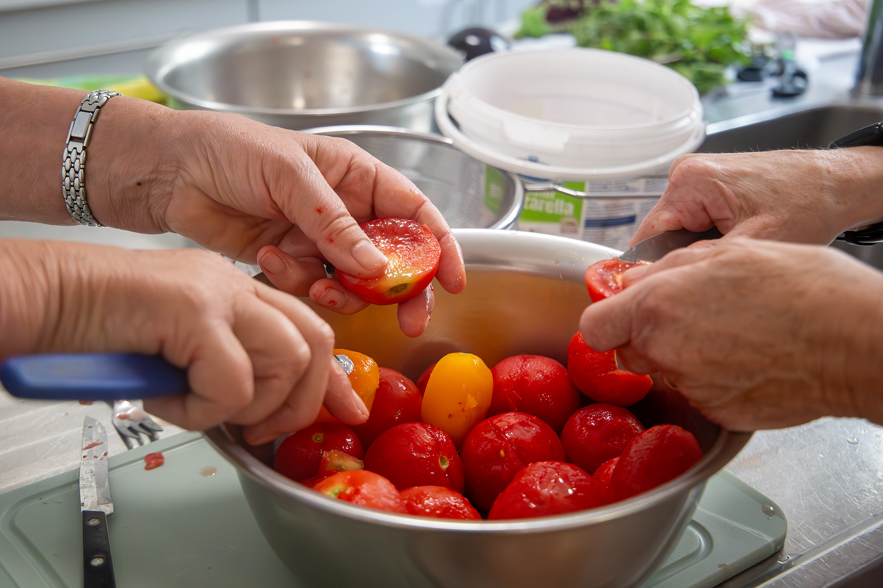Zwei Hände beim Schneiden der Tomaten