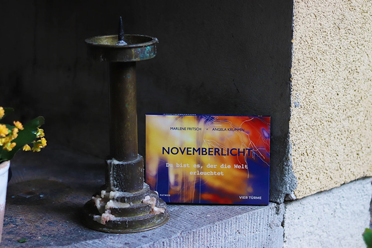 Buch mit buntem Cover steht in einer Nische neben einen Kerzenständer