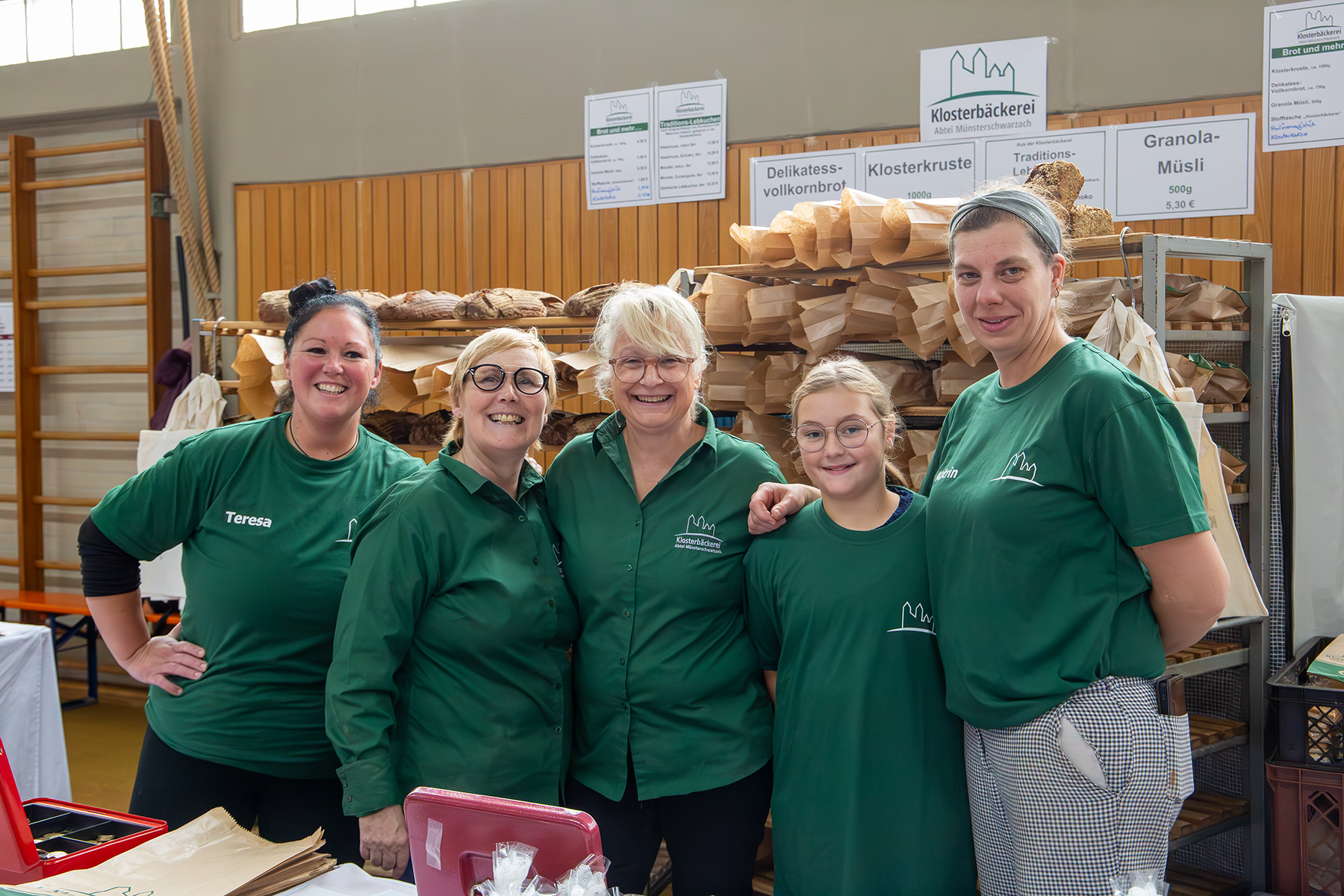 5 Frauen in grünen T-Shirts stehen vor Regalen mit Gebäck