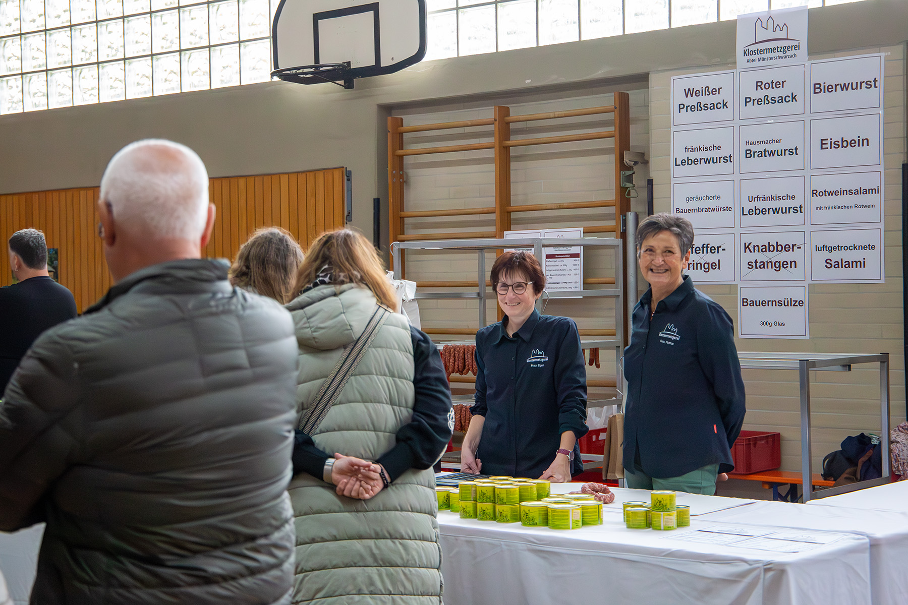 Zwei Frauen hinter Verkaufstisch mit Wurstdosen