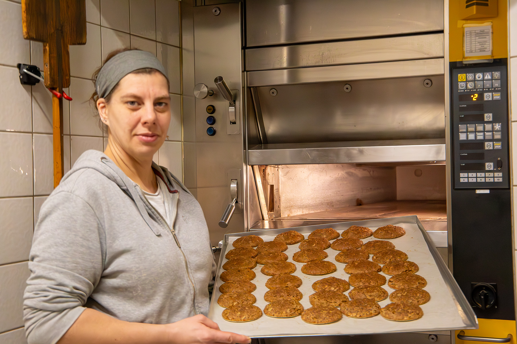 Frau mit Blech voller Lebkuchen vor dem Ofen