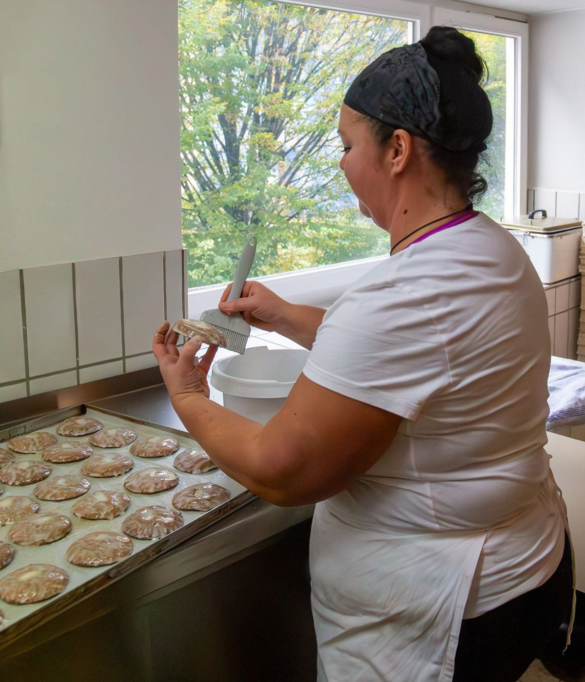 Frau mit weißer Schürz bestreicht Lebkuchen