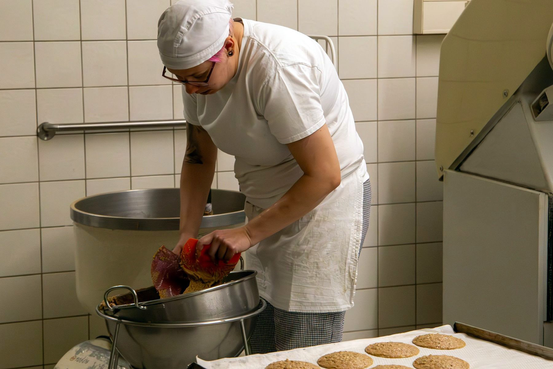 Bäckerin schabt Teig in eine Schüssel