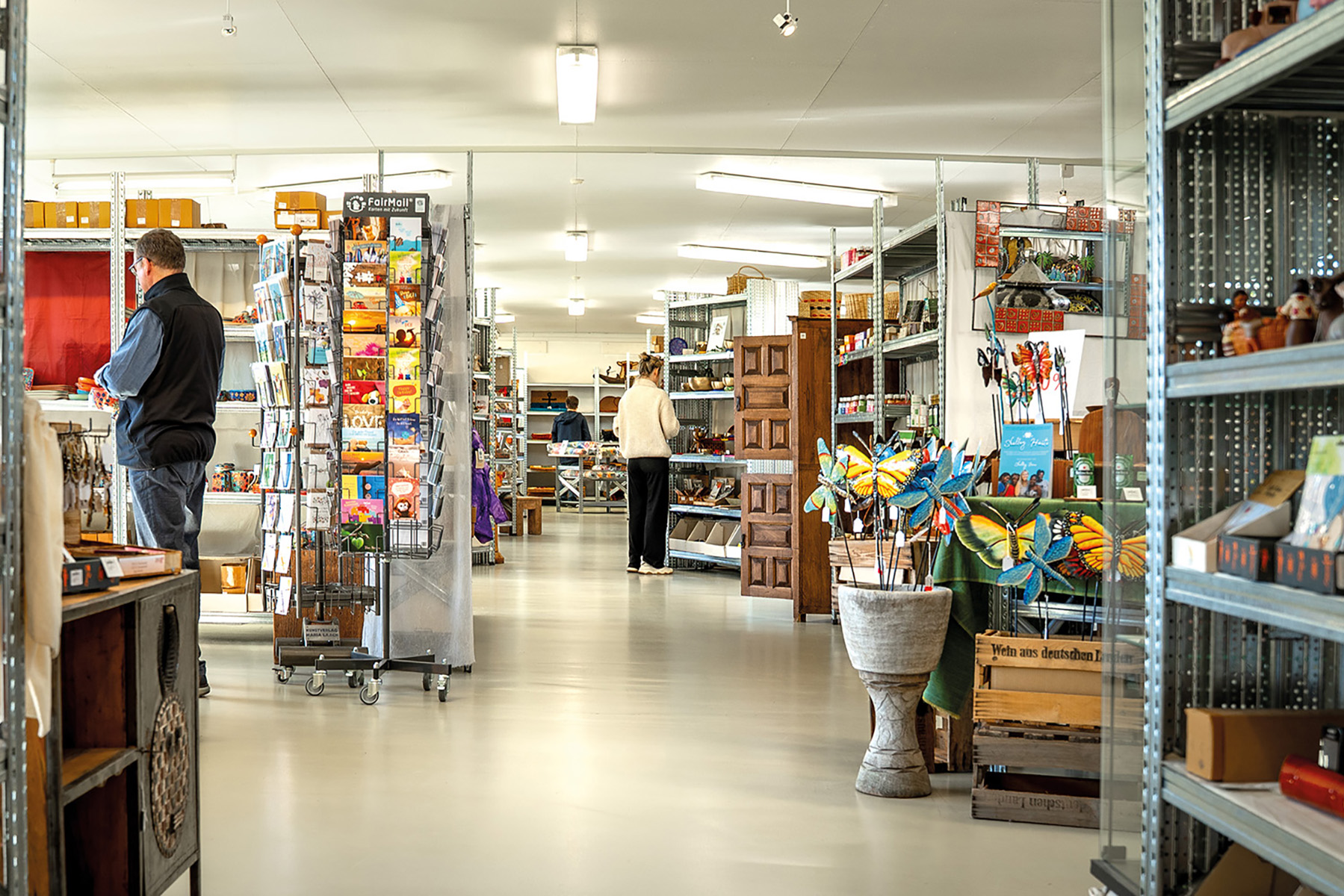 Blick in den Fair-Handel, Menschen stehen vor Regalen voller bunter Produkte