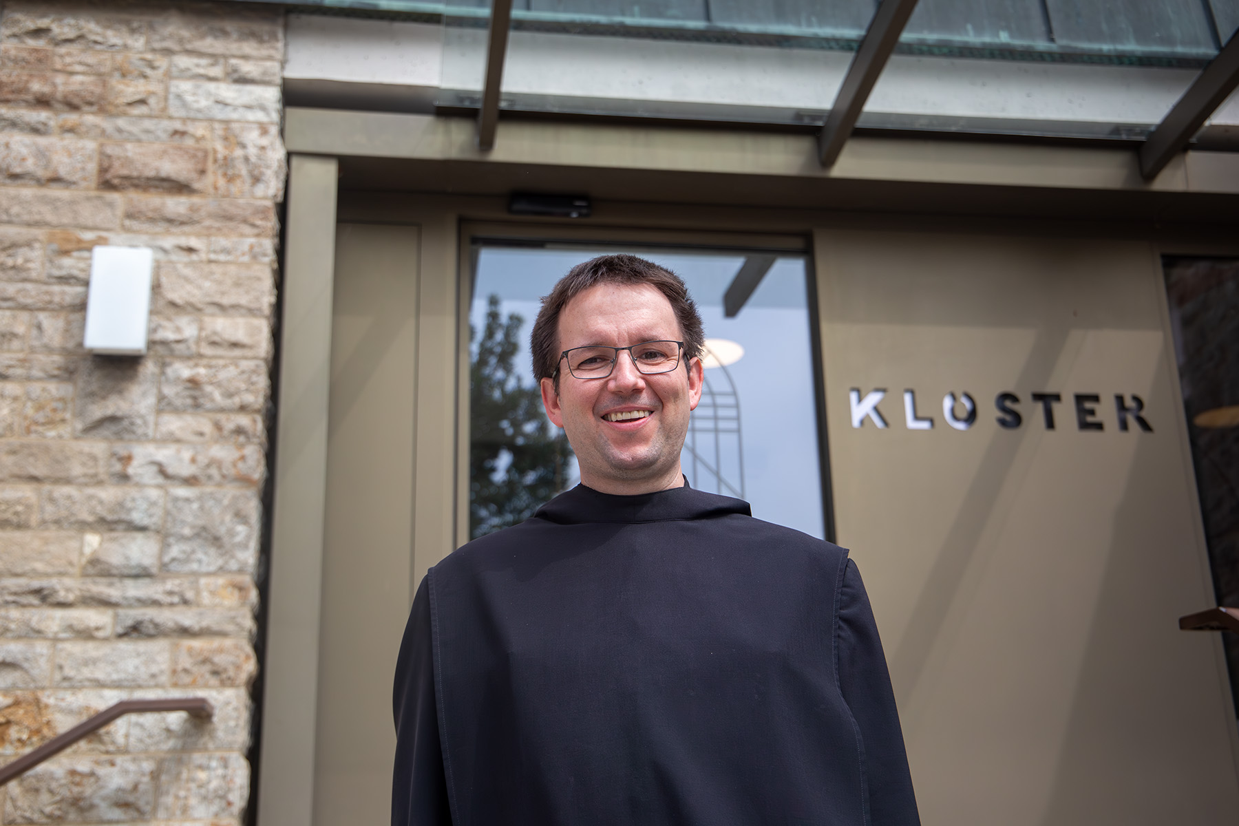 Junger Mönch vor einer Tür, auf der Klosterpforte steht