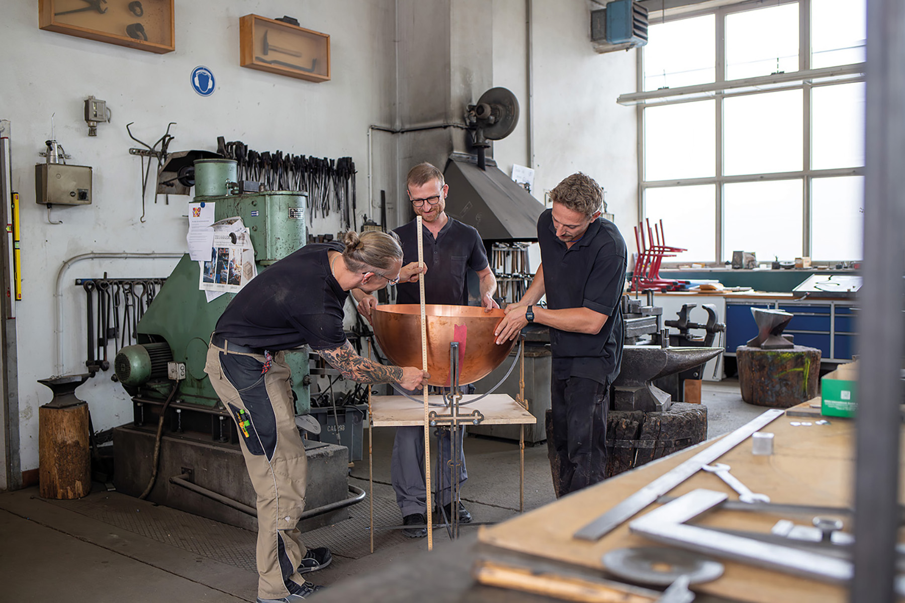 Junge Handwerker arbeiten an einem Kupferkessel