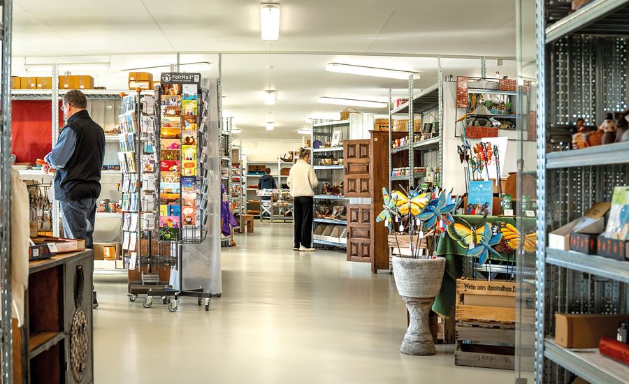 Blick in den Fair-Handel, Menschen stehen vor Regalen voller bunter Produkte