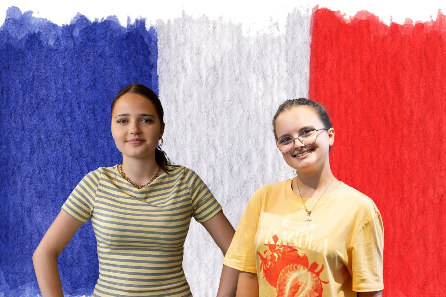 Zwei Schülerinnen vor einer französischen Flagge