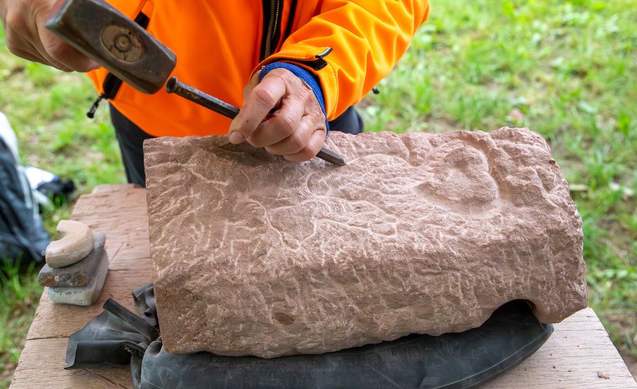 Blick auf Hammer und Meißel, die einen großen Stein bearbeiten