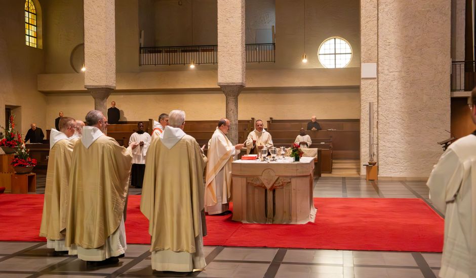Gruppe von Priestern in weißen Gewändern vor einem Tischaltar
