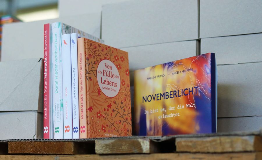 Bücherstapel steht auf einer Holzpalette vor Kartons