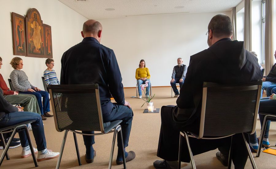 Menschen sitzen im Kreis in einem Tagungsraum
