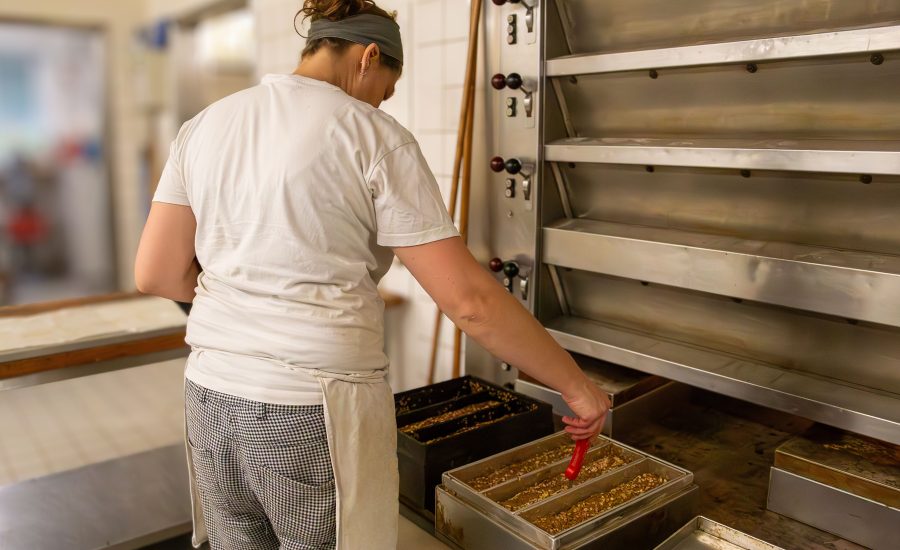 Frau steht am Ofen und misst Temperatur in Brotform