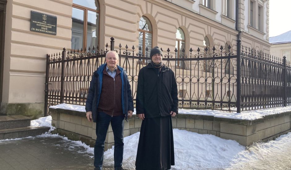 Zwei Männer vor einem Zaun an einem Gebäude