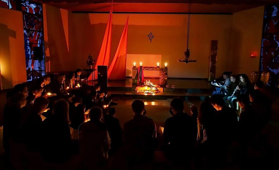 Junge Menschen feiern Andacht in einer mit Kerzen beleuchtenden Kapelle