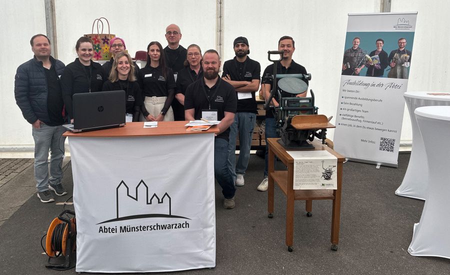 Gruppenfoto mit 5 Frauen und 4 Männern hinter einer Theke mit dem Abtei-Logo