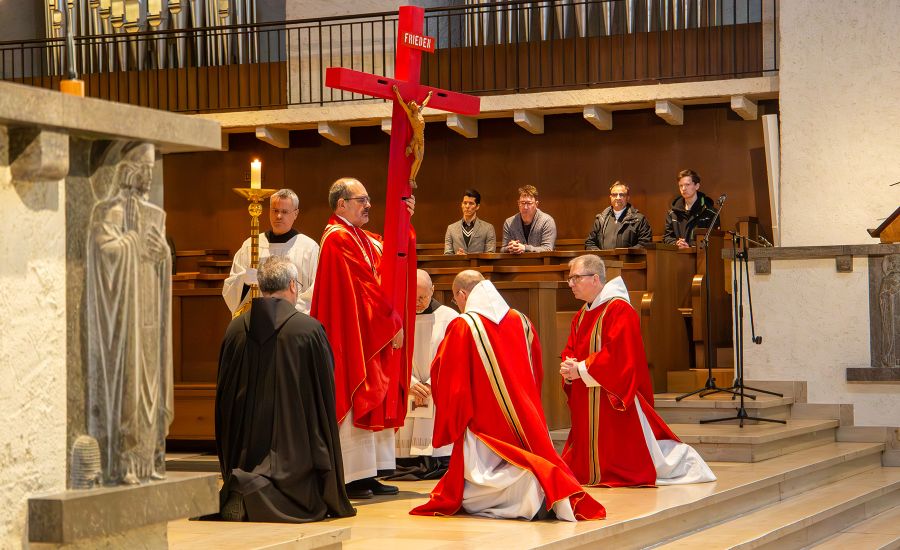 Mönche knien vor rotem Kreuz
